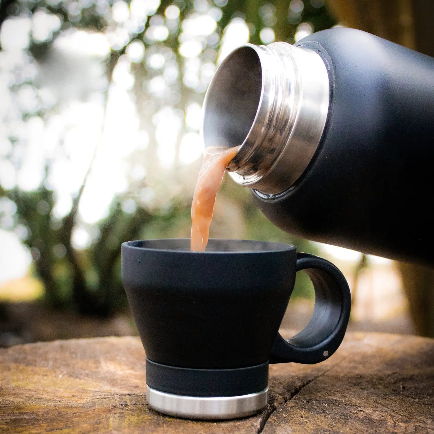 Hot tea being poured from the insulated dog water bottle into its matte black detachable cup outdoors